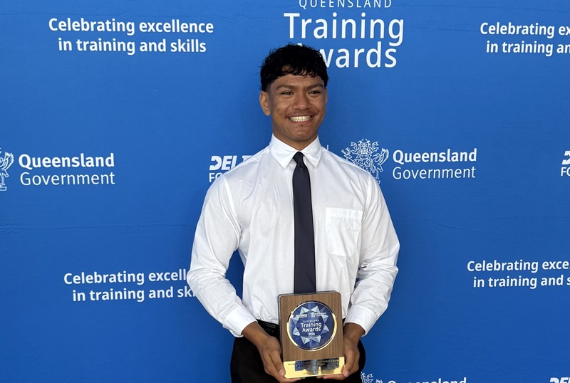 A First Nations teen stands with a training award