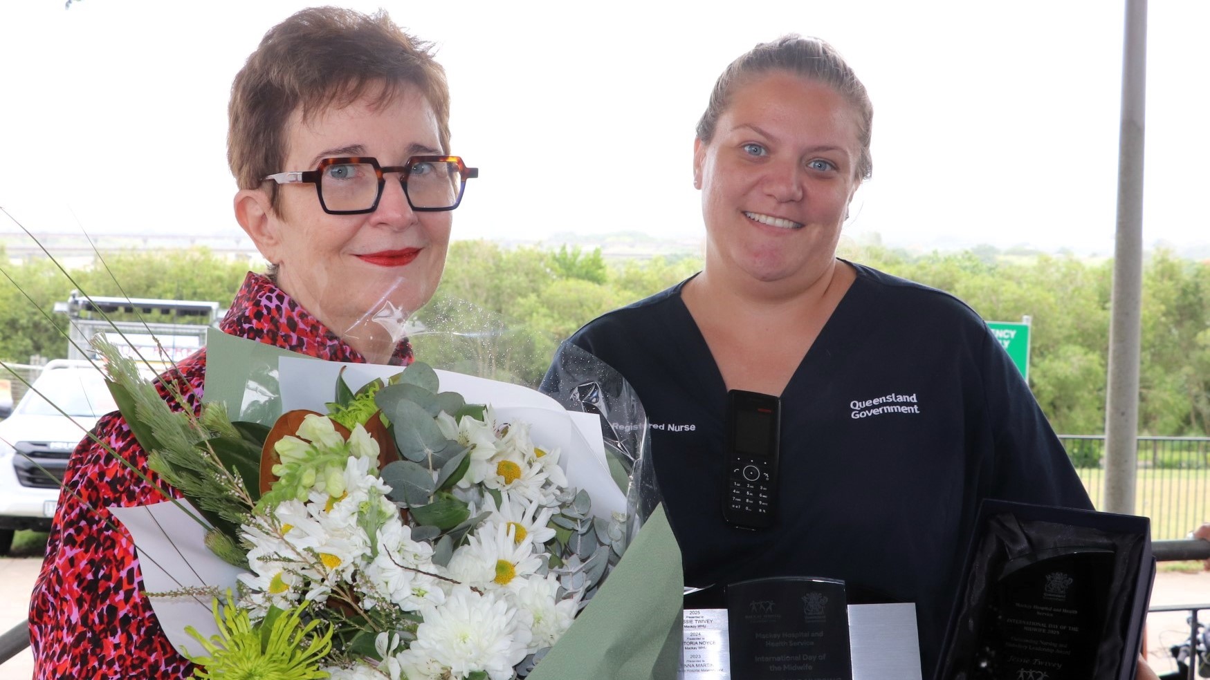 Midwife in blue scrubs is presented flowers
