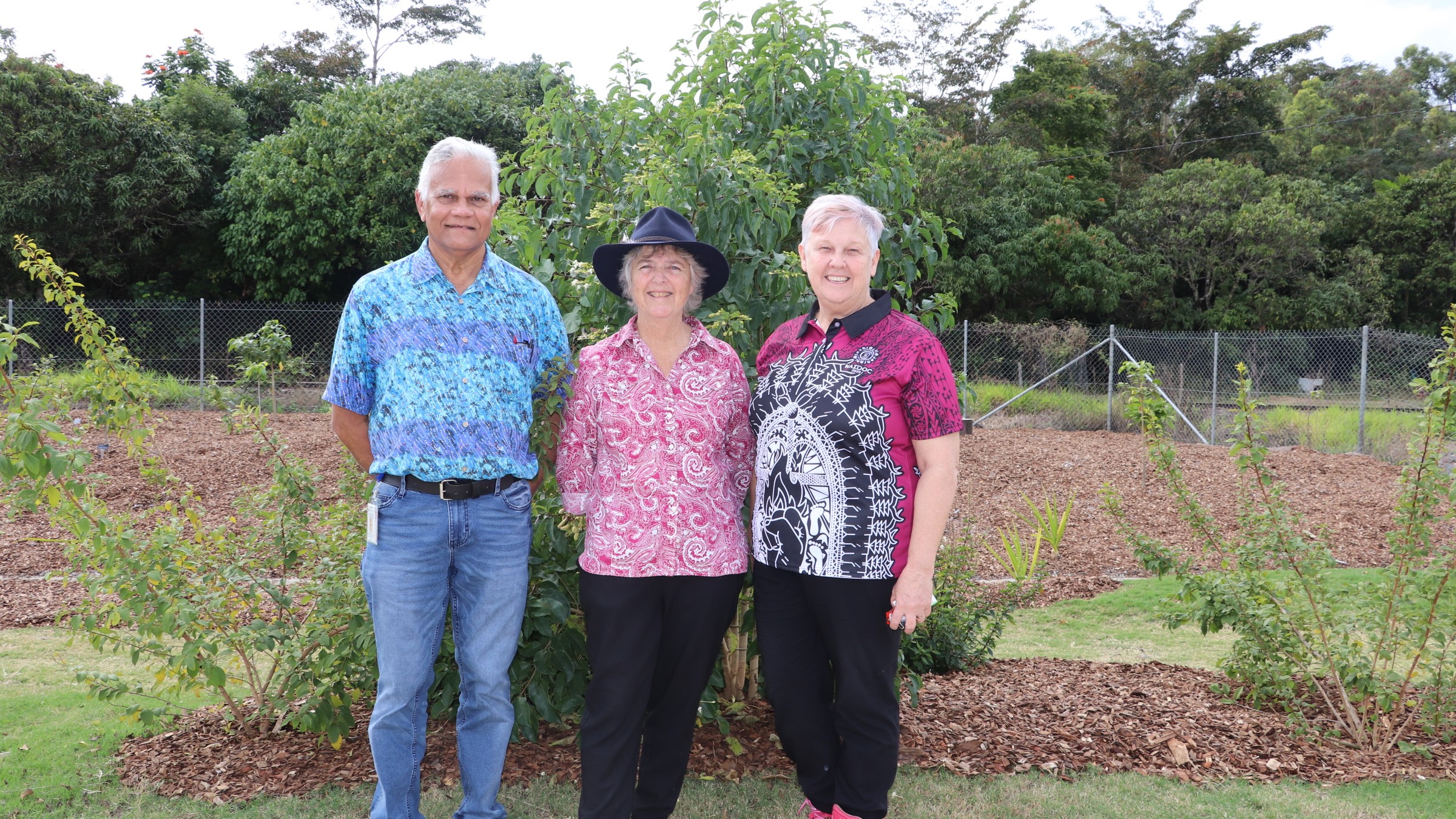 Yuwi elder, volunteer and hospital director of nursing stand in a traditional bush medicine garden