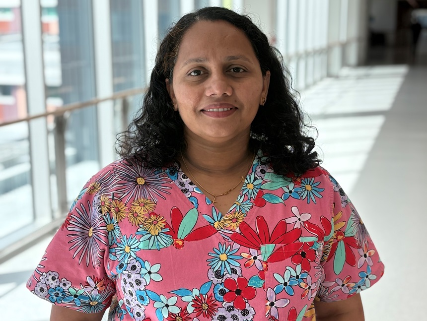 A nurse in colourful scrubs stands in hallway