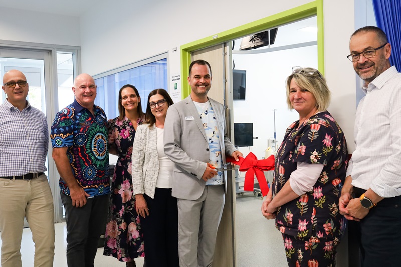 A group stand in front of the ICU with a ribbon to be cut