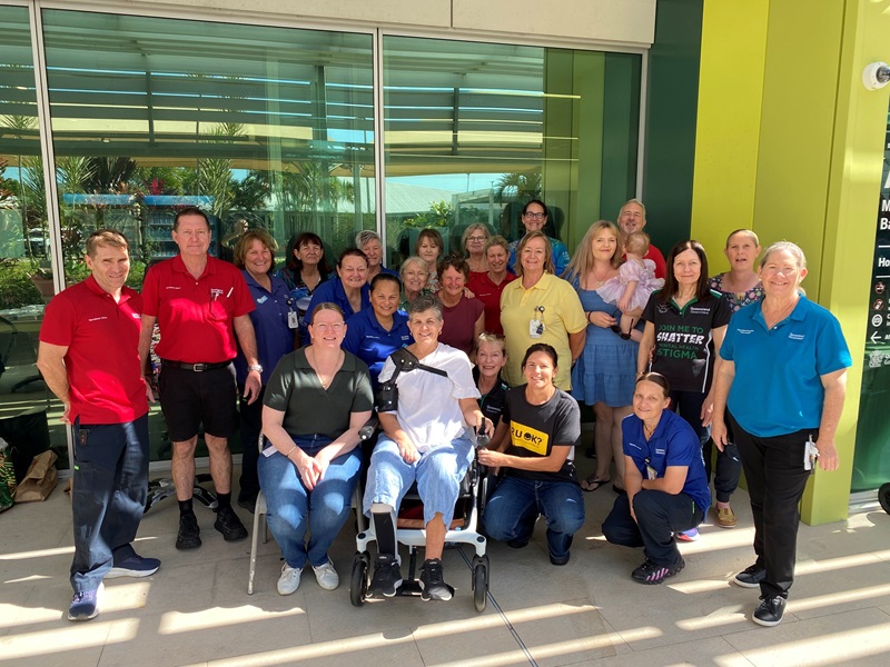 Woman in a wheelchair shares a photo with a group of colleagues at Mackay Base Hospital
