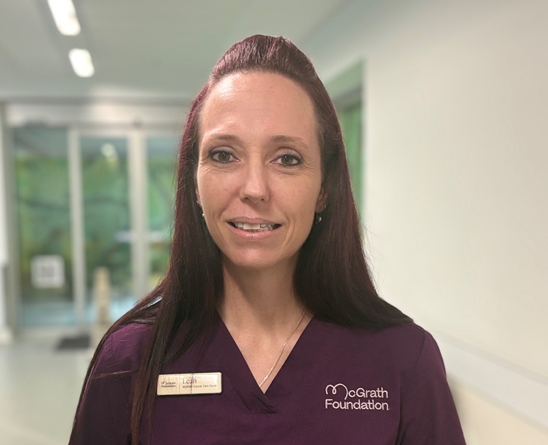 A McGrath nurse in purple scrubs stands in the hospital corridor