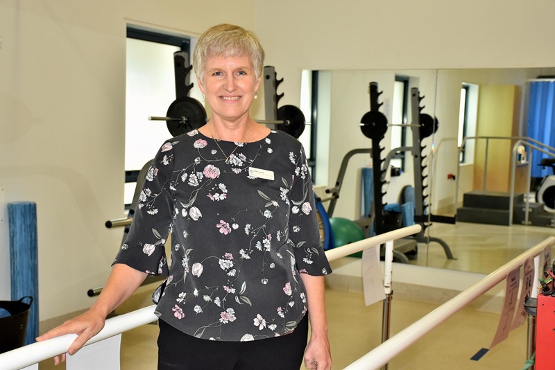 A physiotherapist stands and smiles