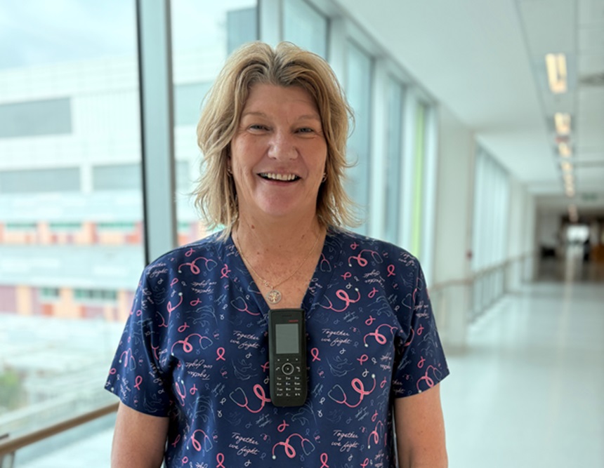 A nurse with blonde hairs stands in the hospital hallway