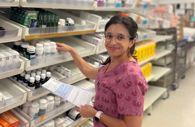 A pharmacist removes medication from shelf