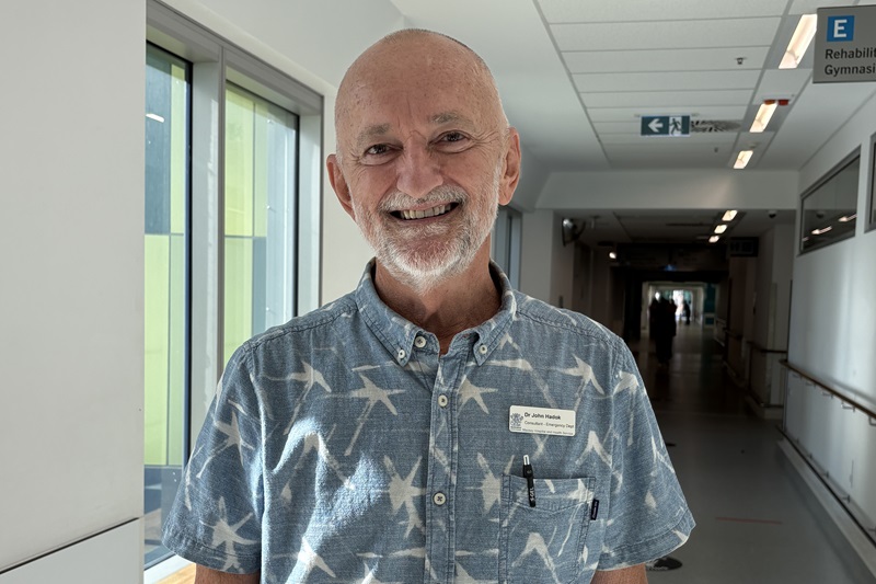 A doctor John Hadok stands smiling in the hospital hallway