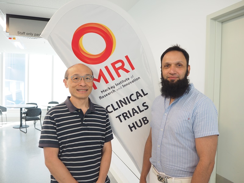 Two doctors stand side by side in front of a MIRI clinical trial banner