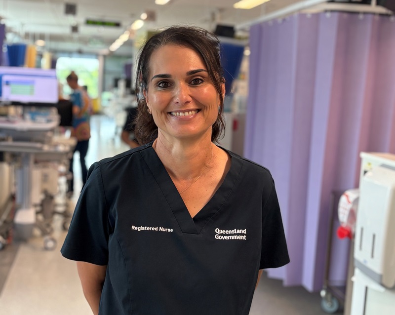 A smiling renal nurse stands in the busy ward