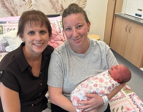 A midwife poses with a mum and newborn bub