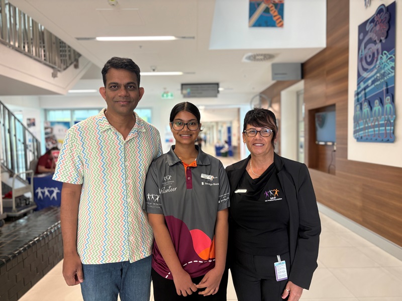 A student volunteer stands with her father and a member of the My Hospital Foundation team