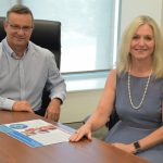 Mackay Hospital and Health Board Acting Chair Darryl Camilleri and Chief Executive Lisa Davies Jones sit at the Board room table with the annual report.