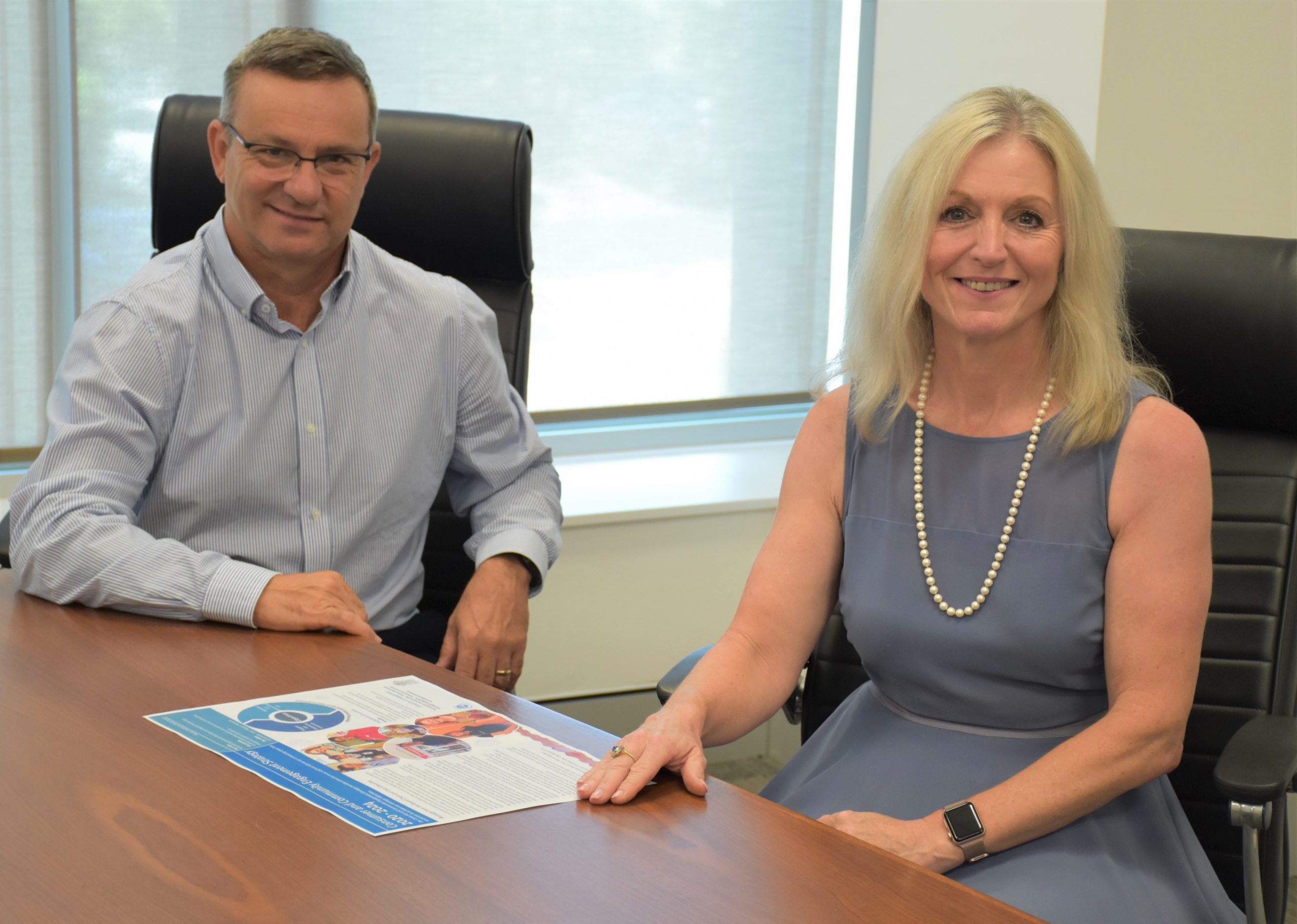 Mackay Hospital and Health Board Acting Chair Darryl Camilleri and Chief Executive Lisa Davies Jones sit at the Board room table with the annual report.